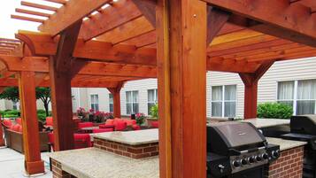 An outdoor patio with a wooden pergola, red seating, and a built-in grill.