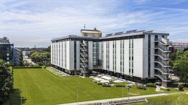 Un edificio moderno con un patio central, varios pisos y una fachada de vidrio y metal.