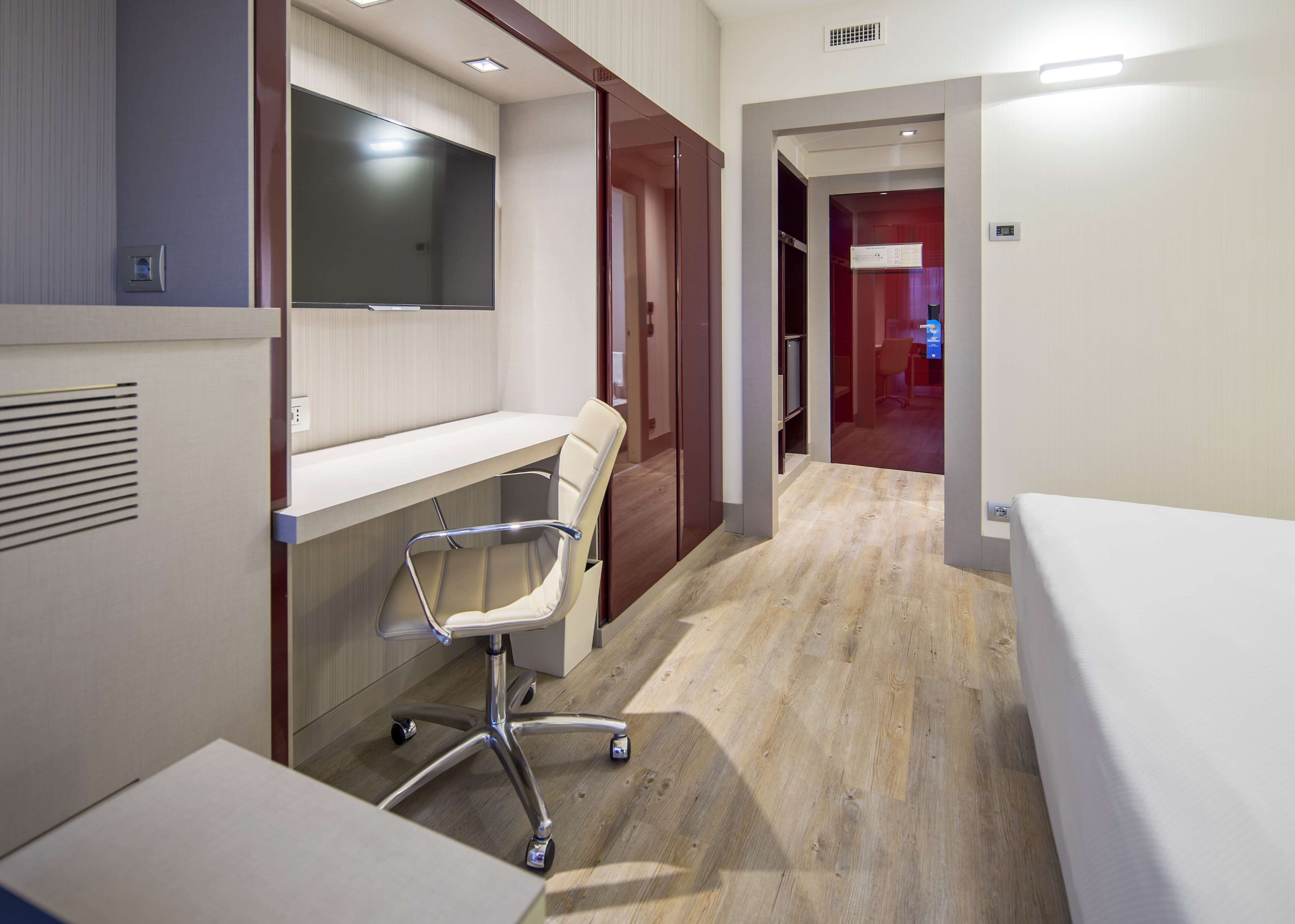 Ein modernes Hotelzimmer mit Schreibtisch, Stuhl und Bett.