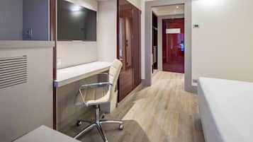 Ein modernes Hotelzimmer mit Schreibtisch, Stuhl und Bett.