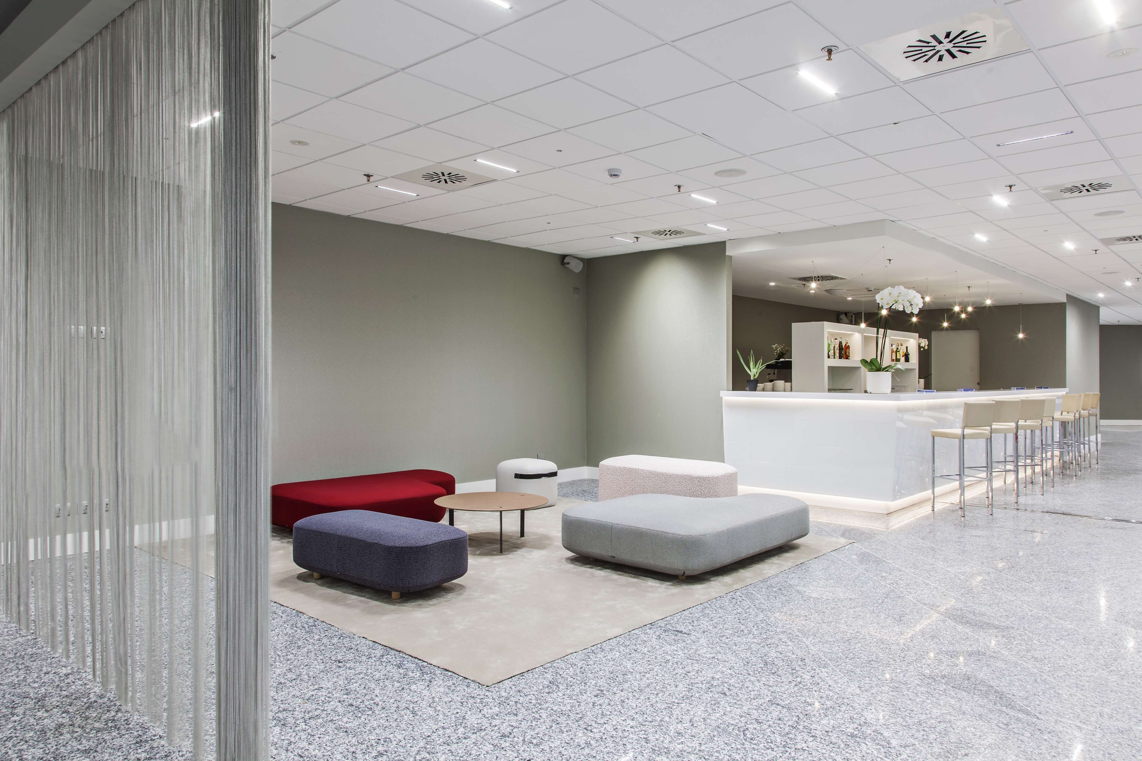 A modern lobby with a reception desk, seating area, and a decorative plant.