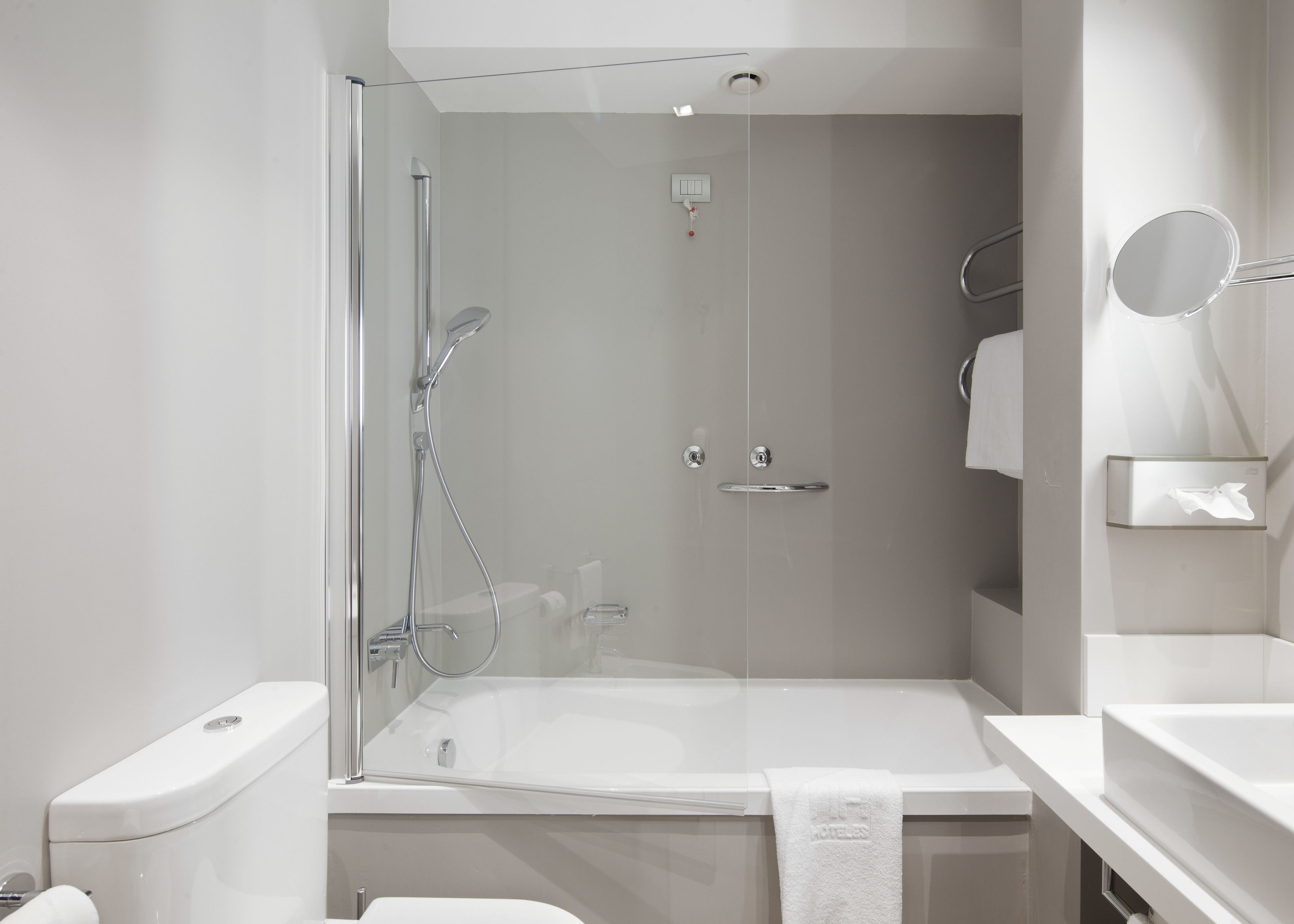 Un bany modern amb dutxa d'estuc de vidre, banyera blanca i un lavabo amb mirall.