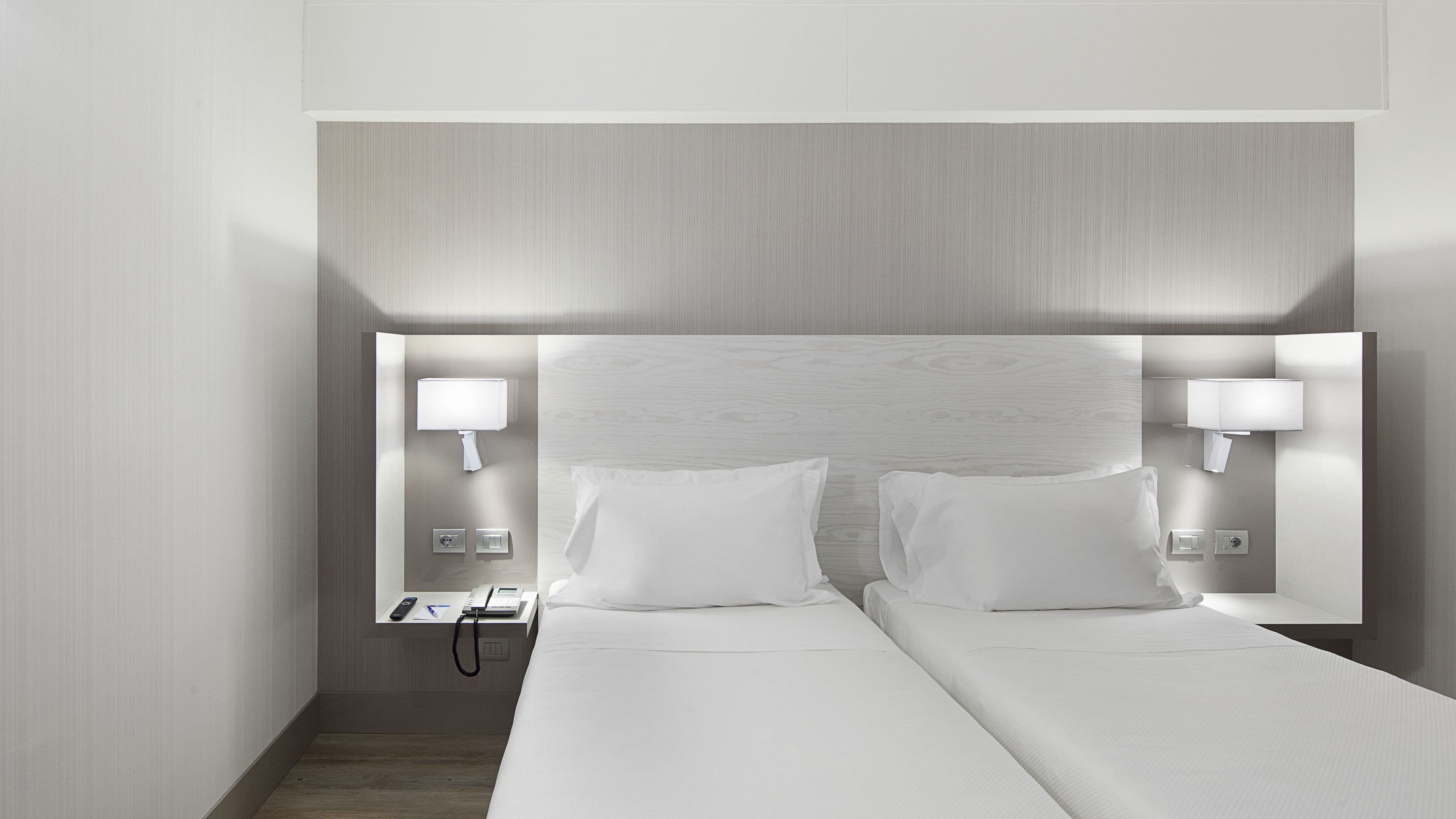 Ein Hotelzimmer mit einem großen Bett, zwei Nachttischen, einer Wandlampe und einem kleinen Tischchen.