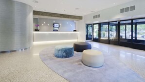 Un área de recepción moderna con un muro curvo, un mostrador de recepción y tres zonas de estar redondas.