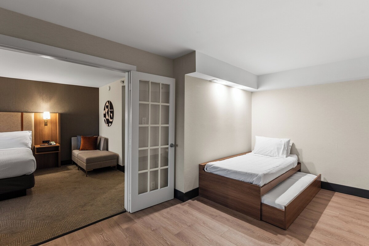 A hotel room with a bed, a sofa, a small table, and a door.