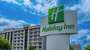Señal de Holiday Inn con un edificio moderno al fondo.