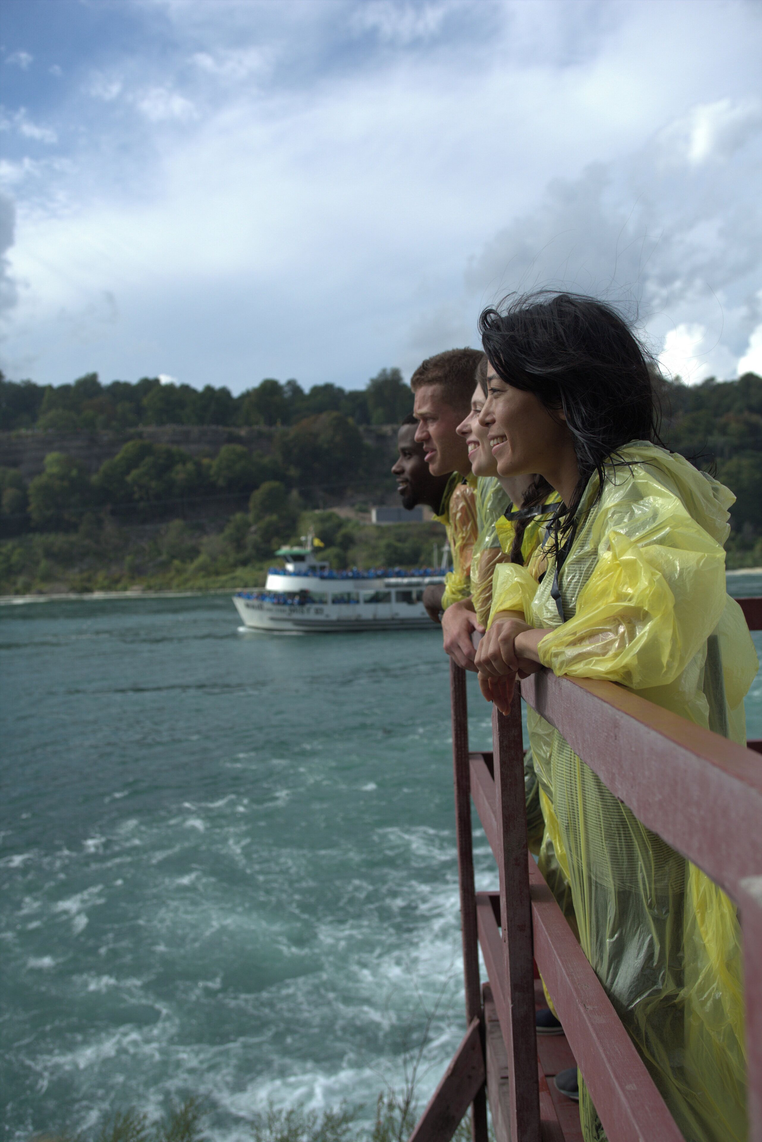 Une rivière avec un bateau au loin et des personnes sur un pont.