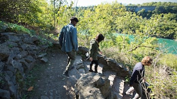 A rocky hiking trail with a view of a river and forest.
