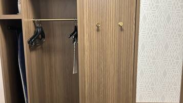 A wooden wardrobe with two doors, a hanging rod, and a small shelf.