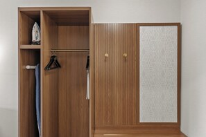 A wooden wardrobe with a geometric patterned panel, a hanging iron, and a coat rack. - Holiday Inn Niagara Falls State Park Entry by IHG (Niagara Falls)