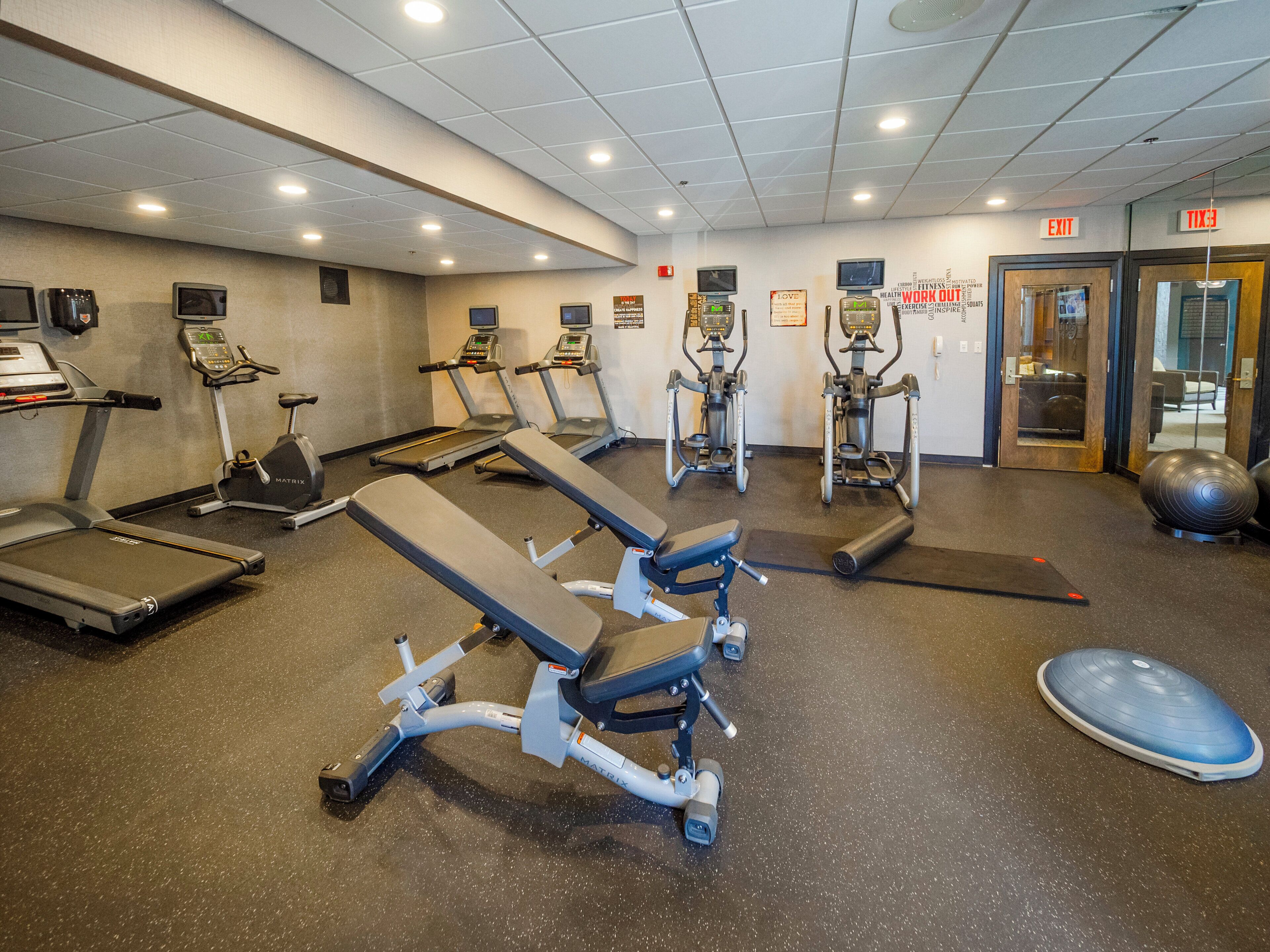 A gym with treadmills, elliptical machines, and weightlifting equipment.