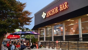 An outdoor seating area of Anchor Bar with tables and umbrellas. - Holiday Inn Niagara Falls State Park Entry by IHG (Niagara Falls)