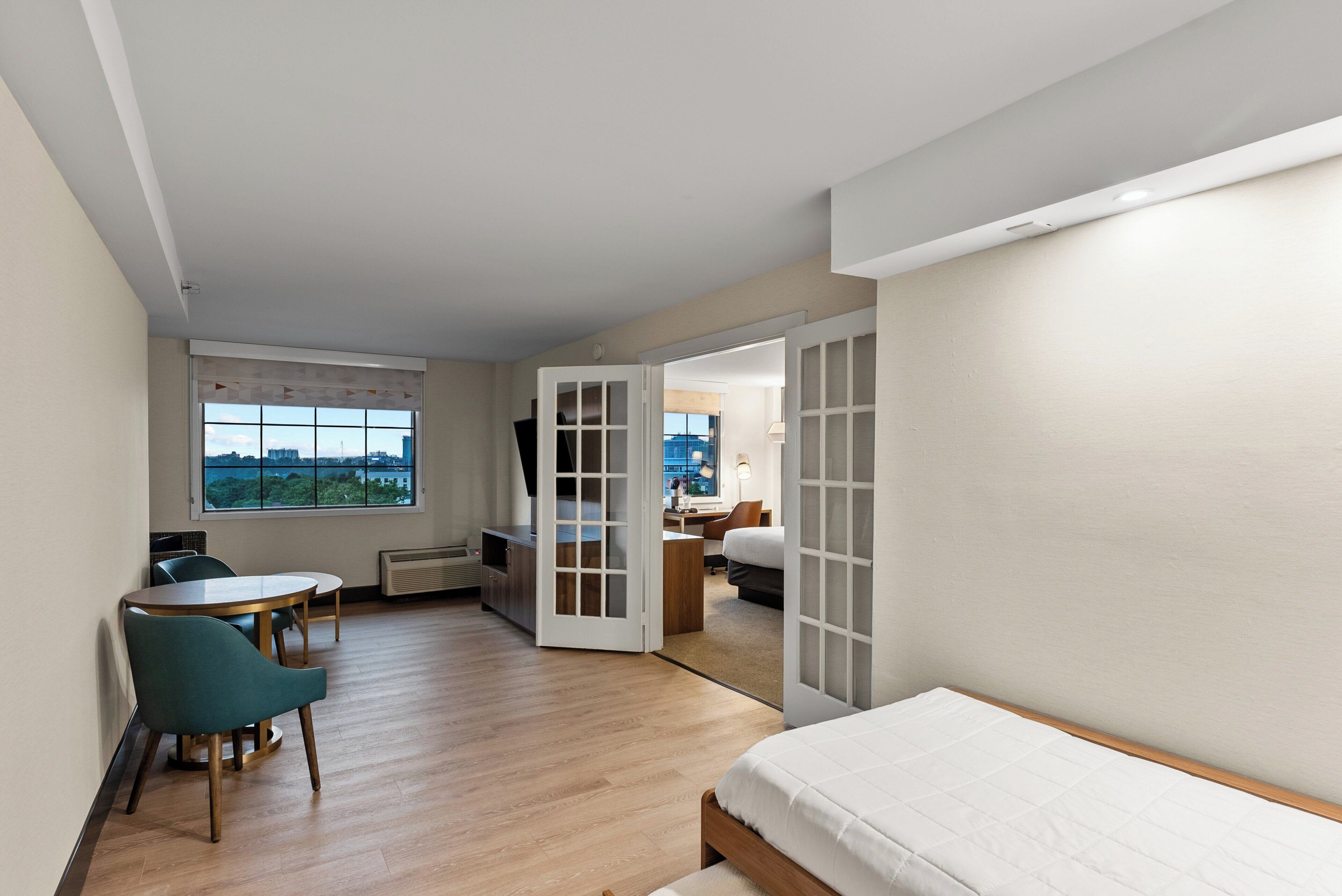 Een moderne hotelkamer met een bed, een bureau en een stoel. Er is uitzicht op de stad door het raam.