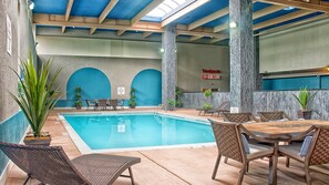 An indoor swimming pool with lounge chairs and tables, surrounded by walls with blue arches and a sign indicating no diving allowed. - Holiday Inn Niagara Falls State Park Entry by IHG (Niagara Falls)