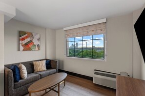 A modern living room with a sofa, a coffee table, a radiator, and a window with a city view. - Holiday Inn Niagara Falls State Park Entry by IHG (Niagara Falls)