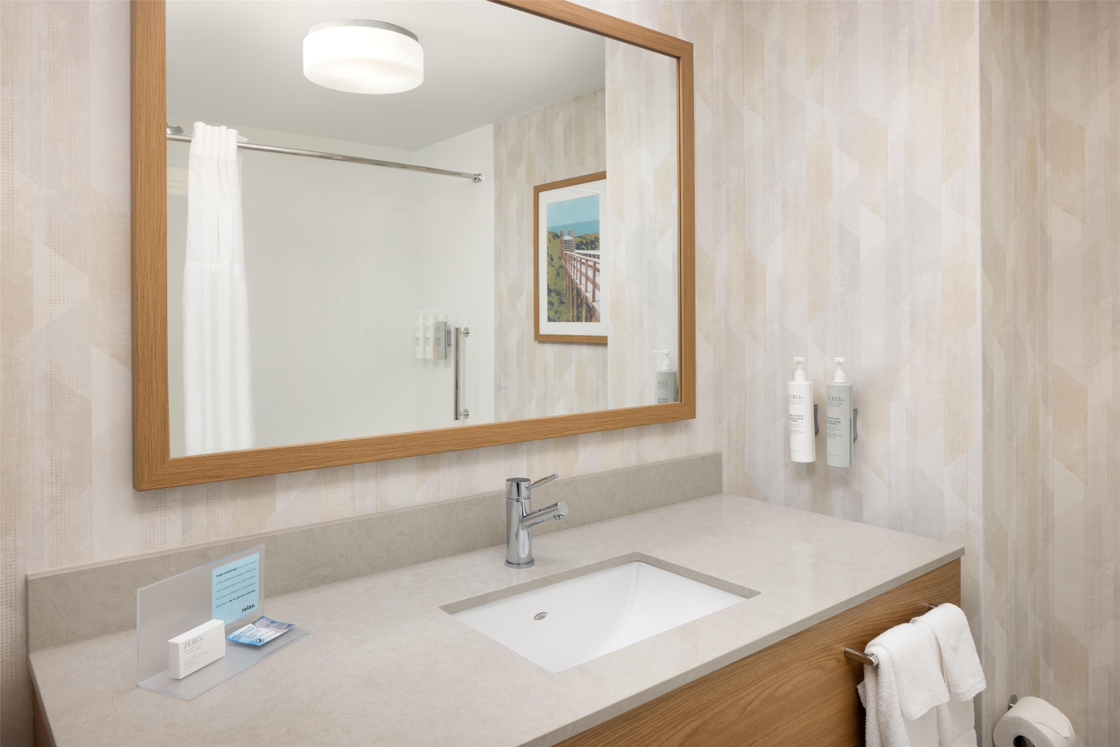 A modern bathroom with a large mirror, a sink, and a towel rack.