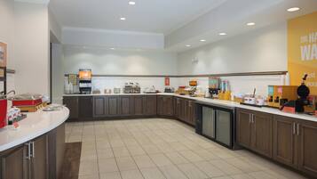 A modern kitchen with dark wooden cabinets, a white countertop, and various appliances.