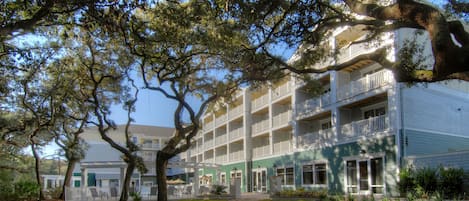A multi-story hotel with balconies, a covered patio, and a well-maintained lawn.