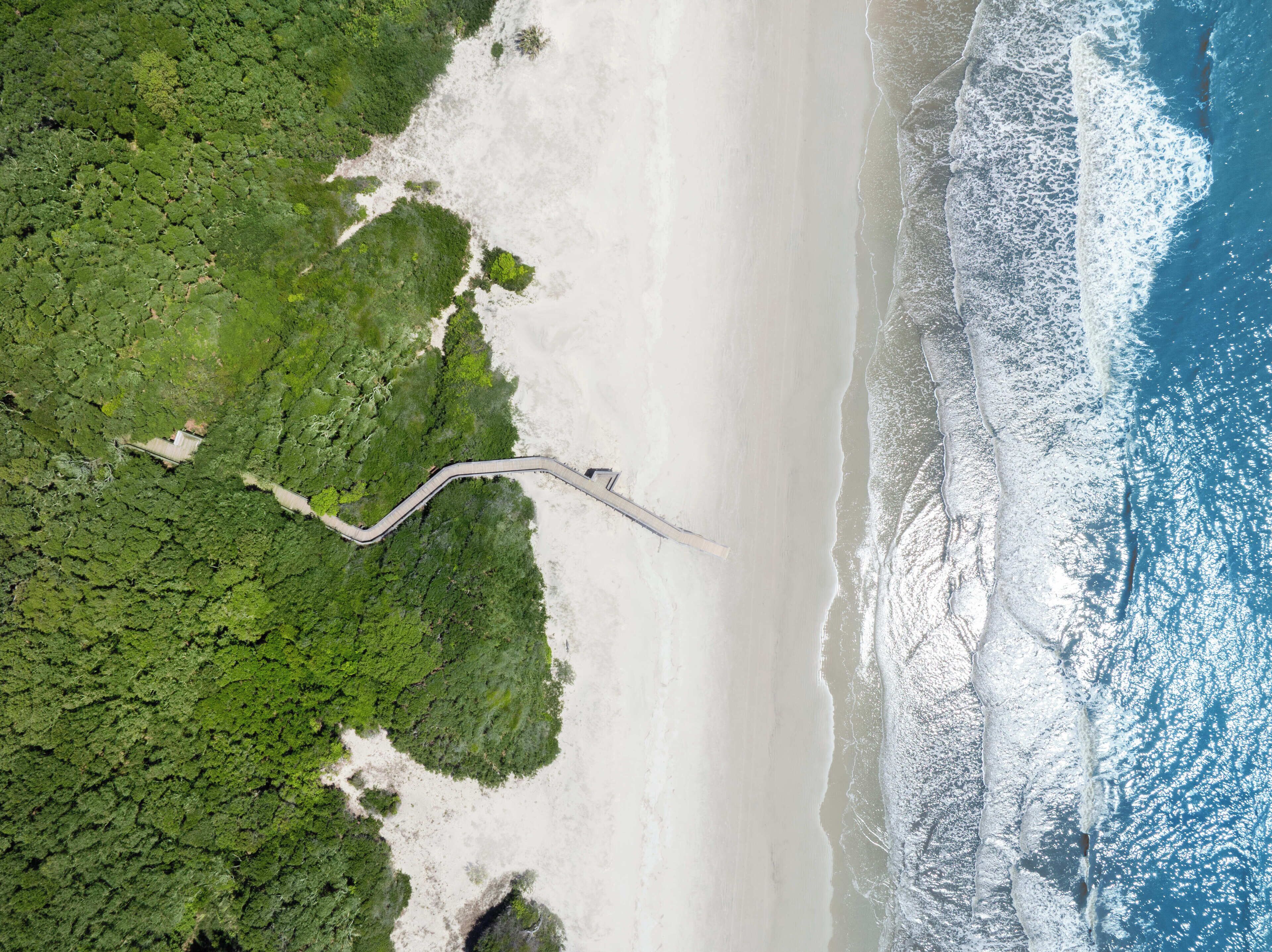 An aerial view of a beach with a winding path leading to a structure.