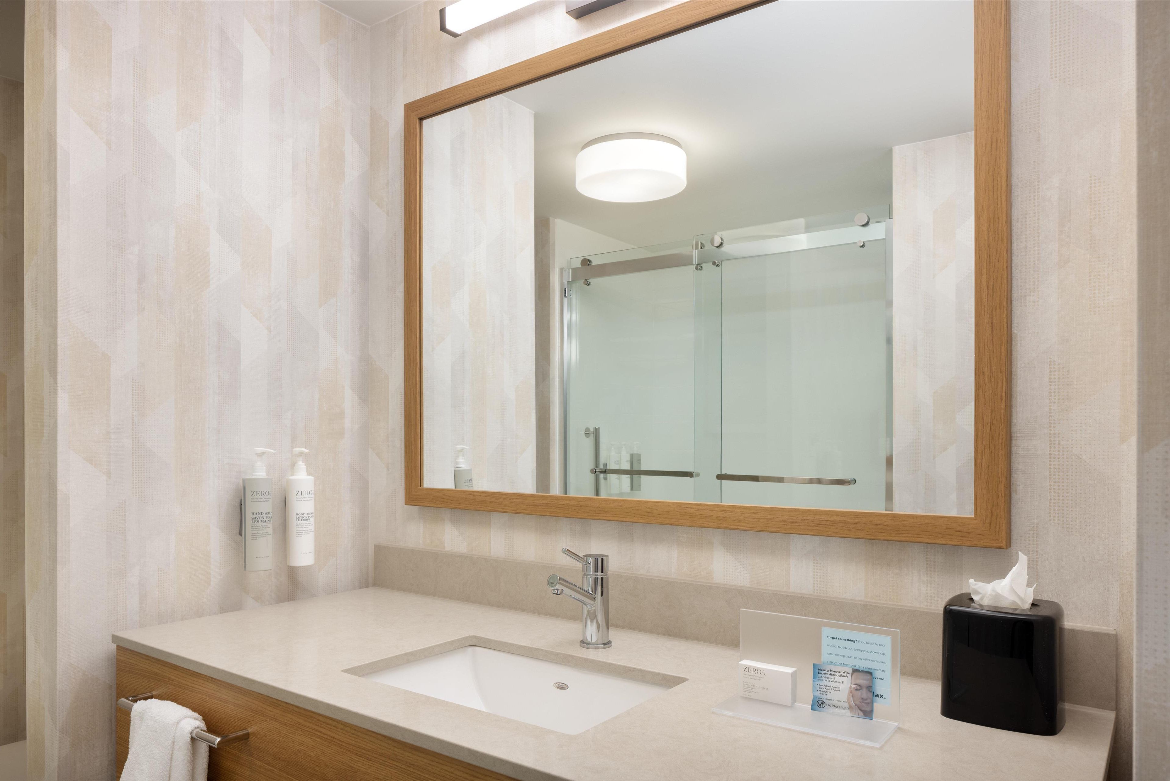 A modern bathroom with a large mirror, a sink, and toiletries.