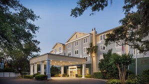 A hotel with a covered entrance, multiple floors, and a landscaped driveway.