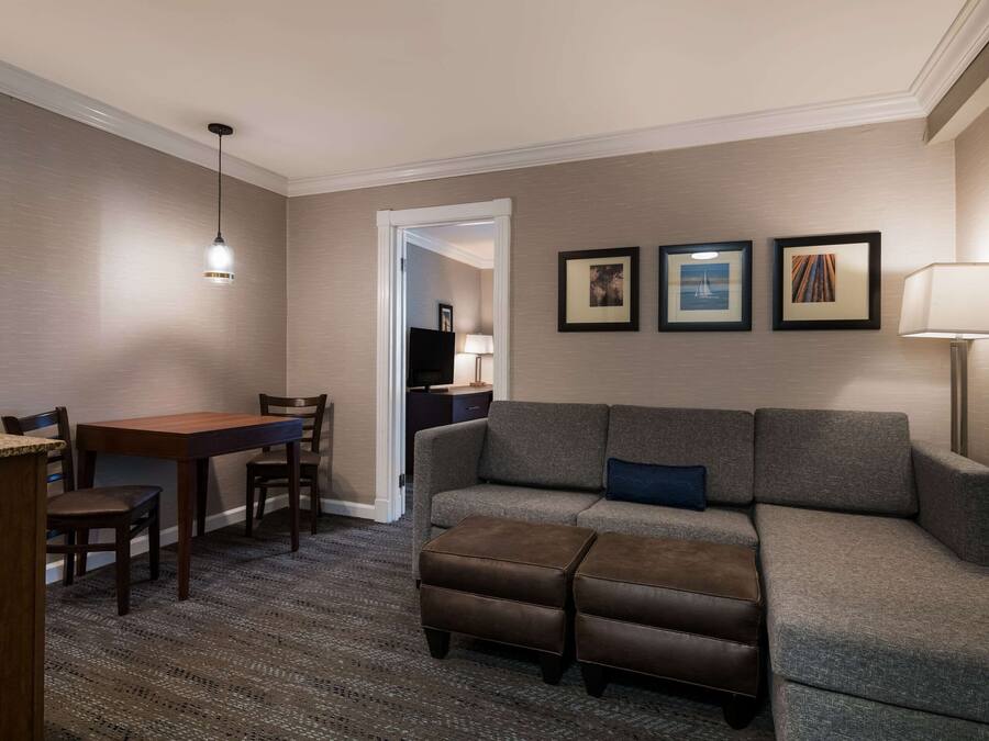 A hotel room with a dining area, a sofa, and a TV in the background.