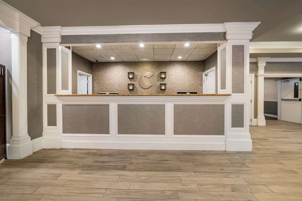 A reception area with a stone wall, a large C-shaped logo, and a wooden floor.