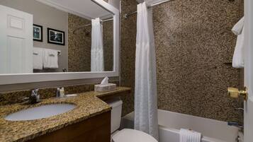 Ein Badezimmer mit Granitwaschtisch, Toilette und Badewanne.