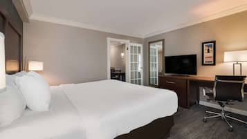 A hotel room with a large bed, a desk with a chair, a television, and a mirror.