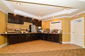 A kitchen with dark wooden cabinets, a countertop with a coffee machine, and a door marked "EXIT".