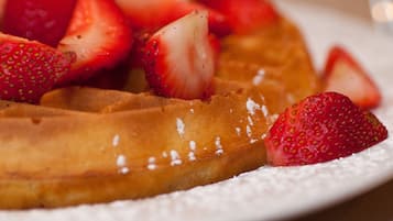 A close-up of a waffle with strawberries on top.
