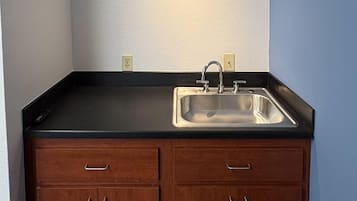 Cocina con encimera negra, pileta de acero inoxidable y armarios de madera.