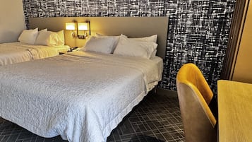 Habitación de hotel con dos camas, una silla, una pared con textura y una mesita.