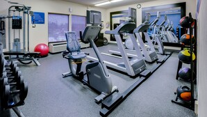 A gym with treadmills, elliptical machines, and free weights.