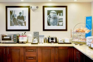 A kitchenette with a coffee maker, microwave, toaster, and a coffee station. - Pittsburgh Airport Inn and Suites (Coraopolis)