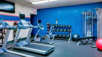 Une salle de sport équipée de tapis de course, d’appareils de musculation et d’un mur rempli d’haltères.