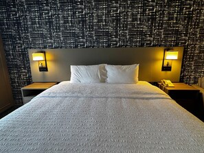 A hotel room with a large bed, two bedside tables, and a patterned wall. - Pittsburgh Airport Inn and Suites (Coraopolis)