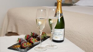 Una botella de champán y dos copas sobre una mesa con fresas y chocolate.