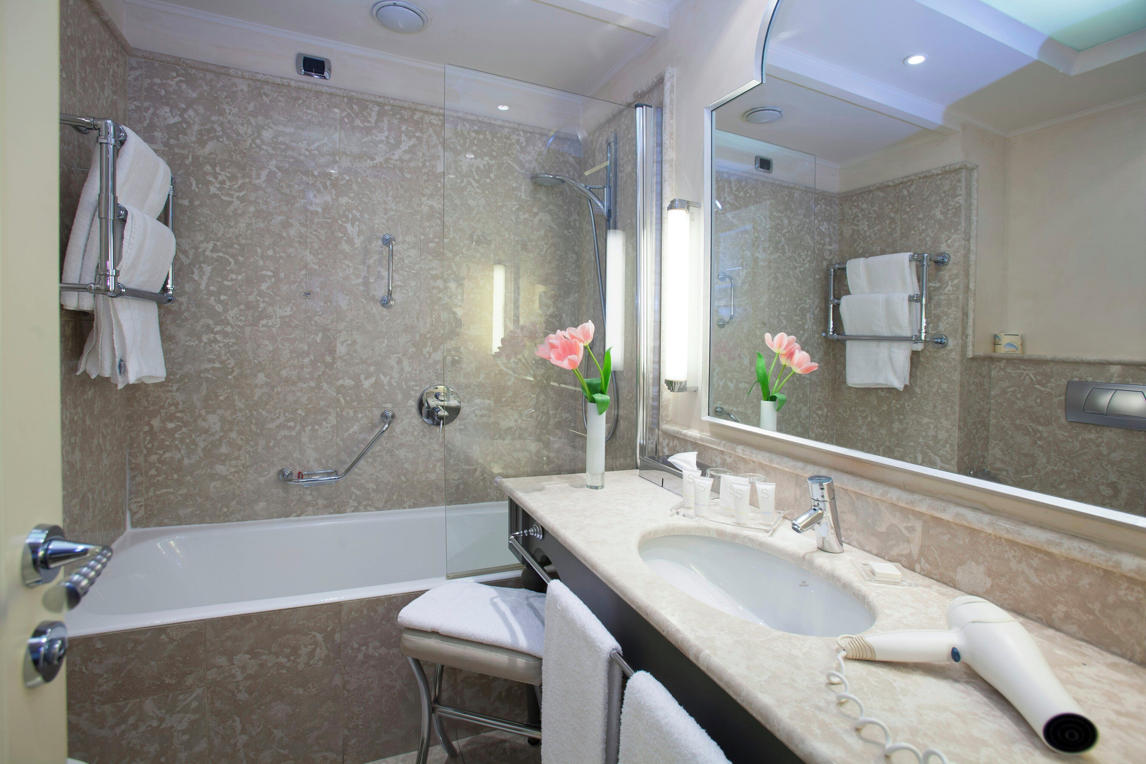 Un baño moderno con una bañera, un lavabo y un espejo grande.