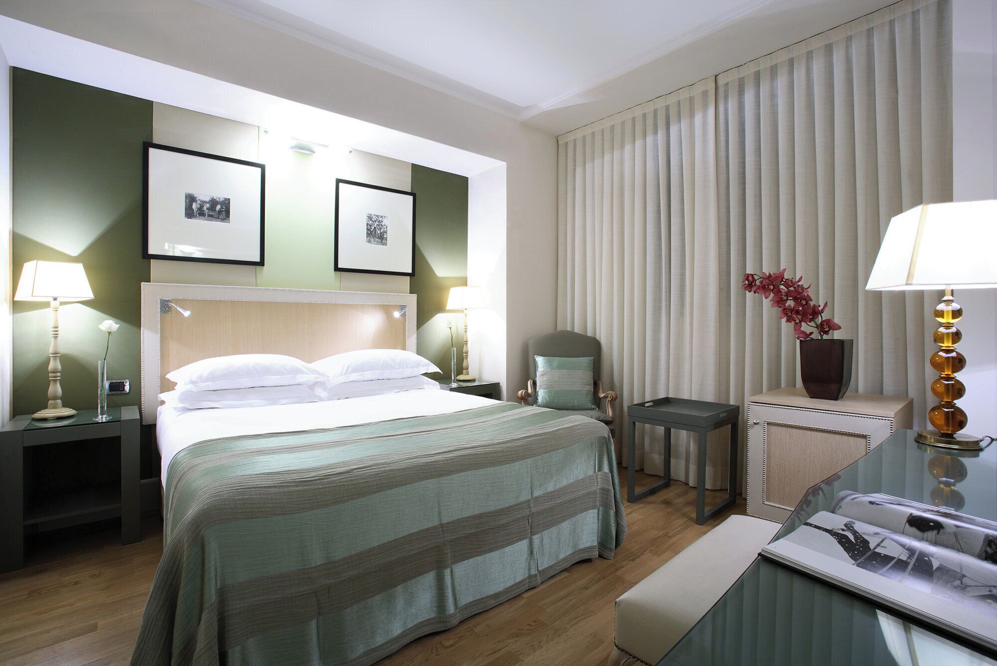A hotel room with a bed, bedside tables, a chair, a desk, and a lamp.