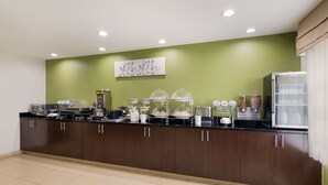 A kitchen area with a green wall, a coffee machine, a refrigerator, and various food items on the counter. - Sleep Inn Tanglewood (Roanoke)