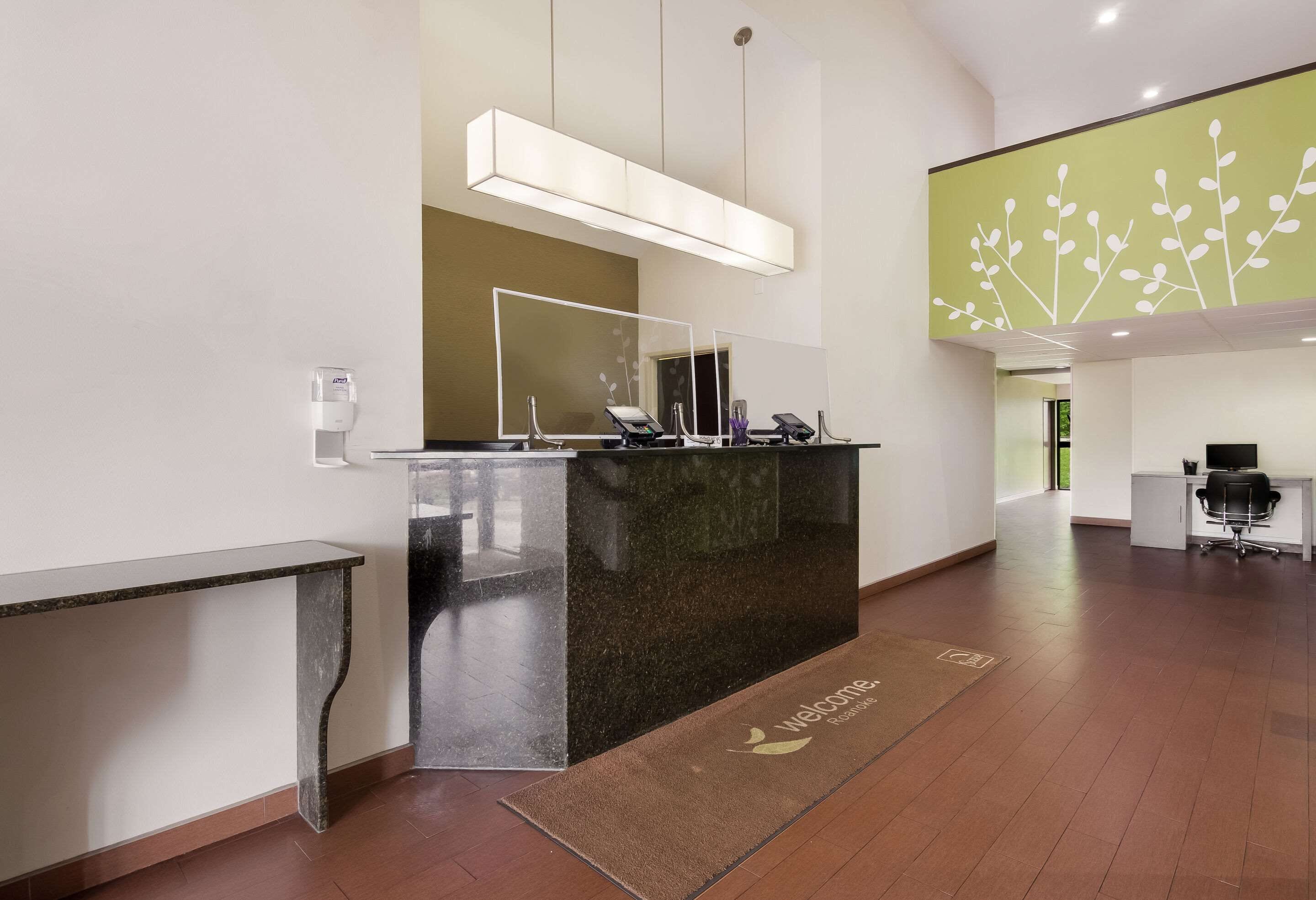 A reception area with a dark marble counter, a large mirror, and a welcome mat.