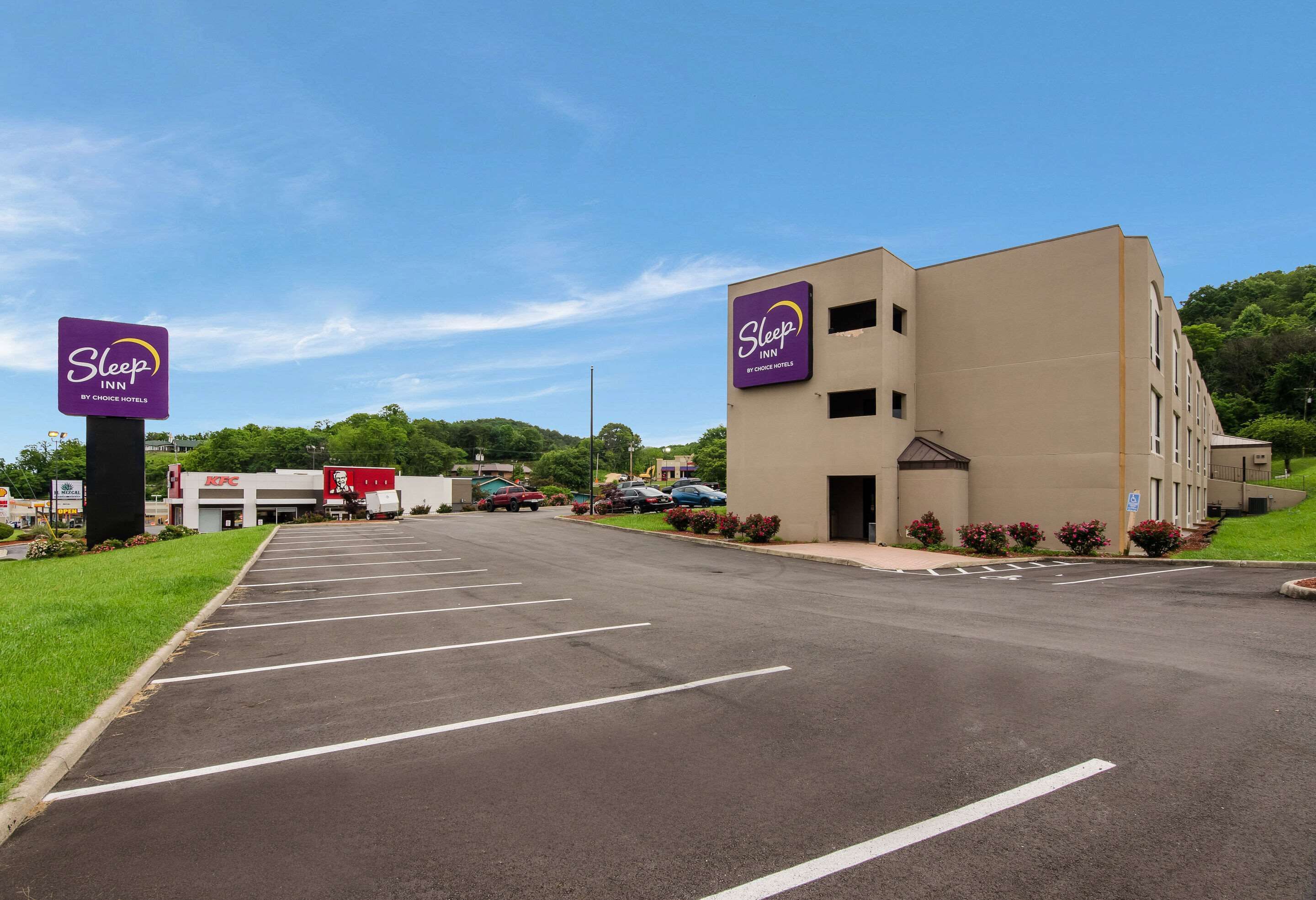 Un Sleep Inn de Choice Hotels con aparcamiento y un edificio de fachada color crema.