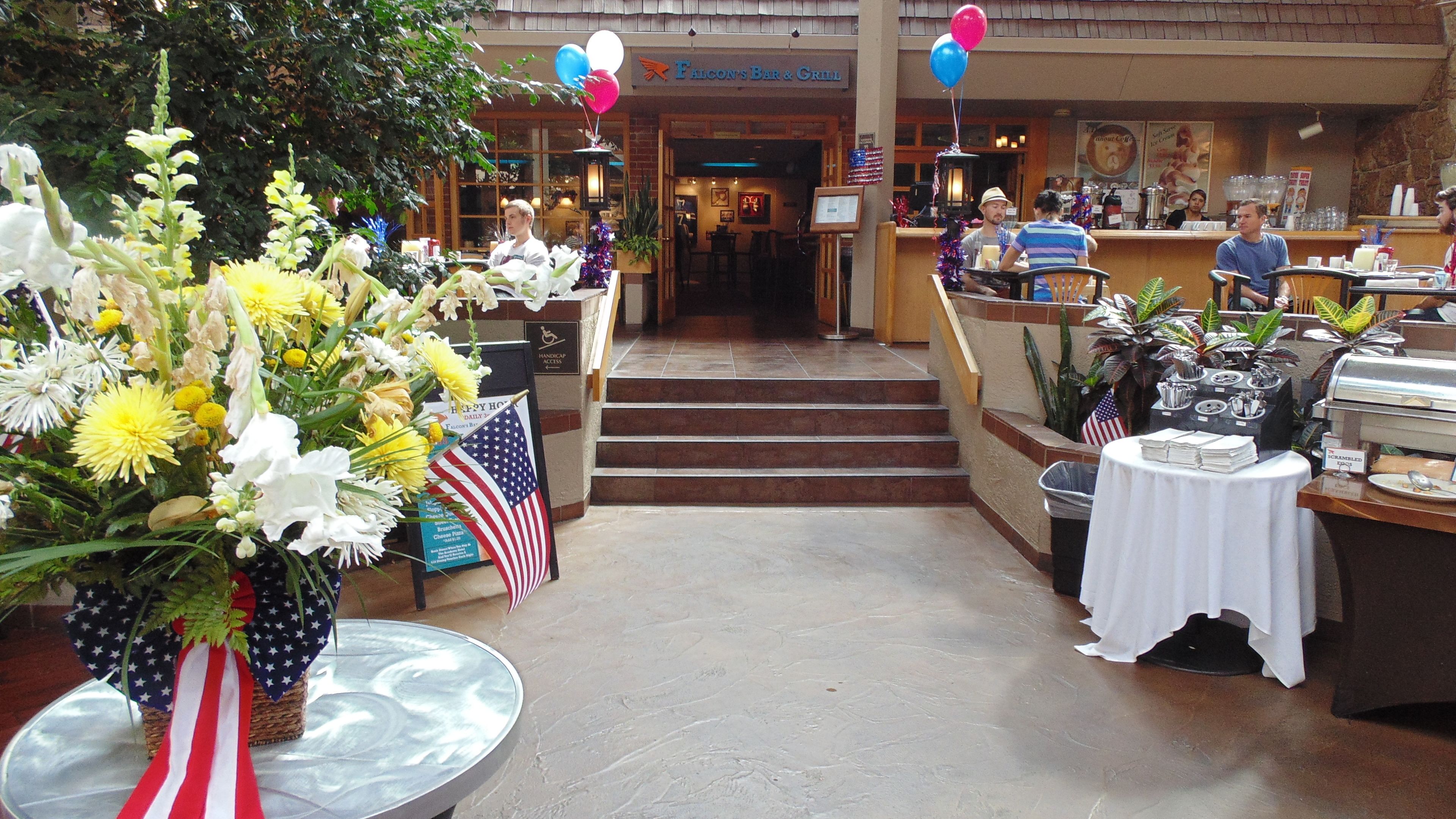 A restaurant with a bar and grill, indoor plants, and a wheelchair-accessible entrance.