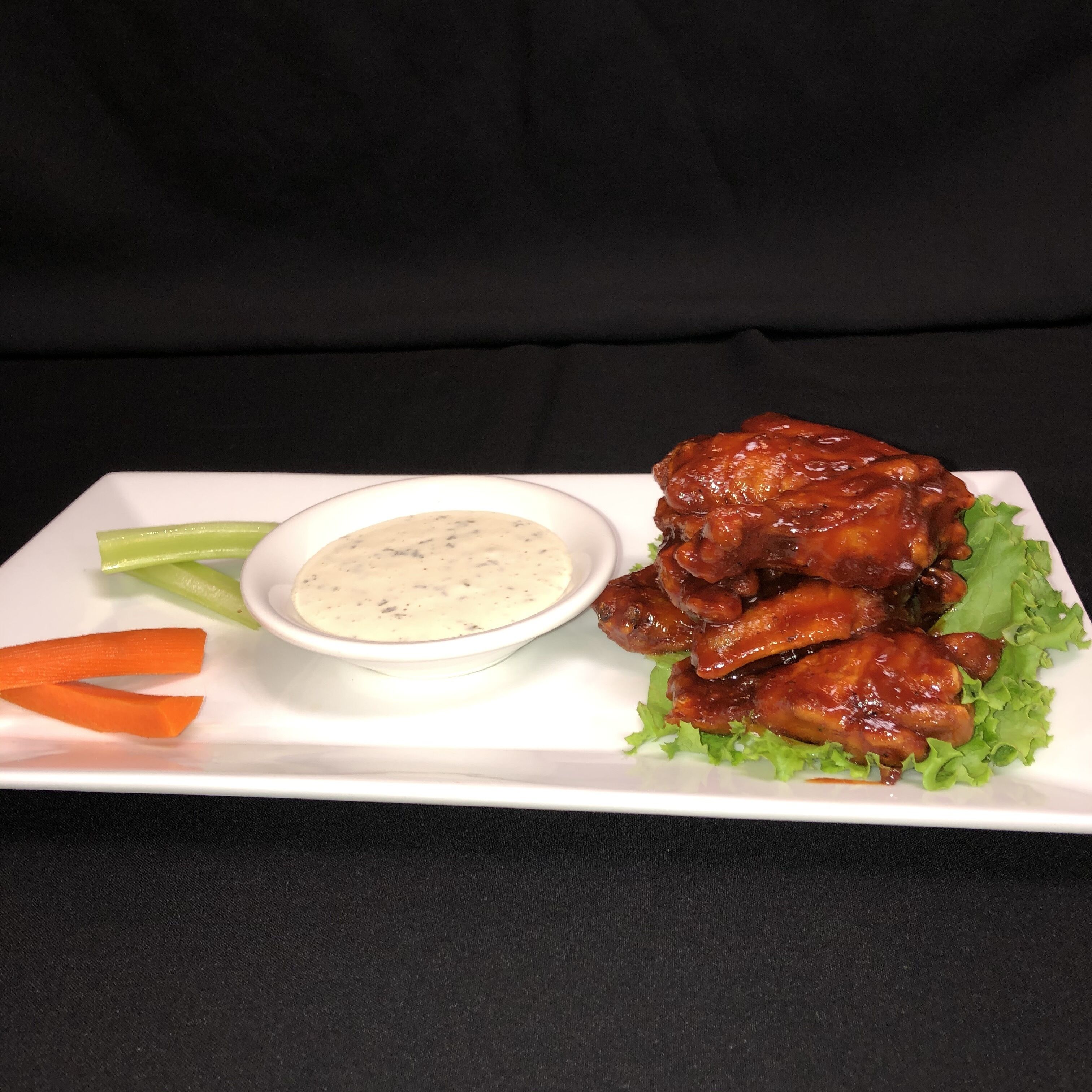 Een bord met vleugels, selderij, wortelstengels en een klein schaaltje saus.