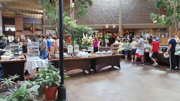 A bustling indoor food court with multiple dining tables and people.
