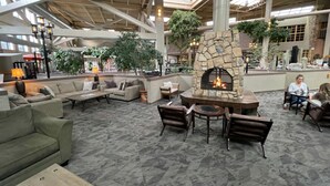 A spacious indoor area with a stone fireplace, comfortable seating, and large windows allowing natural light. - The Academy Hotel Colorado Springs (Colorado Springs)