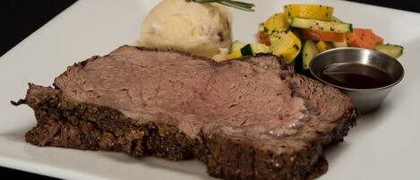 A plate with sliced beef, mashed potatoes, and a side of mixed vegetables.
