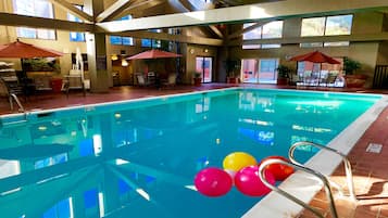Una piscina interior con agua cristalina, rodeada de tumbonas y sombrillas.