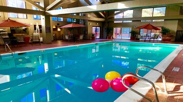 Una piscina interior con agua cristalina, rodeada de tumbonas y sombrillas.
